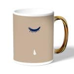 كوب قهوة بمقبض ذهبي بتصميم عيون تبكي